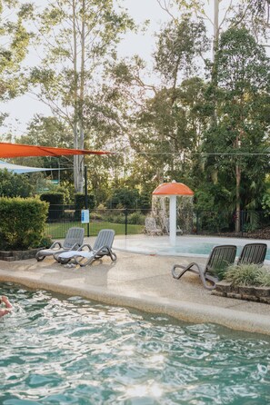 A poolside area with lounge chairs, a water fountain, and a covered seating area. - Ingenia Holidays Noosa (Tewantin)