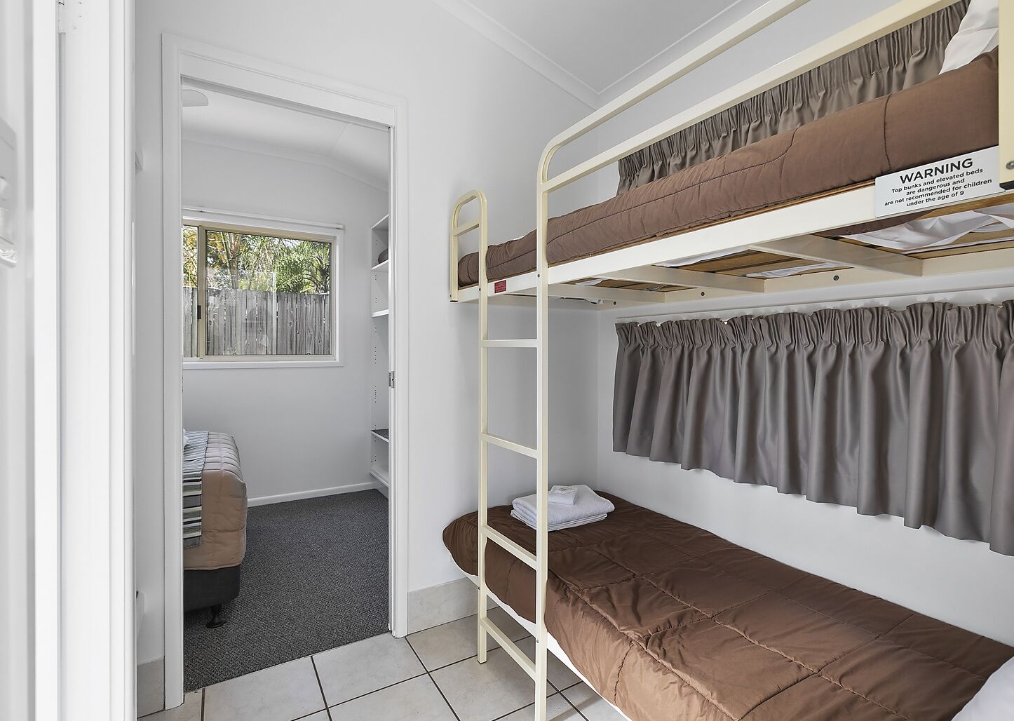 Quarto com beliche, um aviso, uma janela e um sofá.