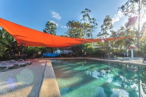 A clear swimming pool with lounge chairs and a shaded area. - Ingenia Holidays Noosa (Tewantin)
