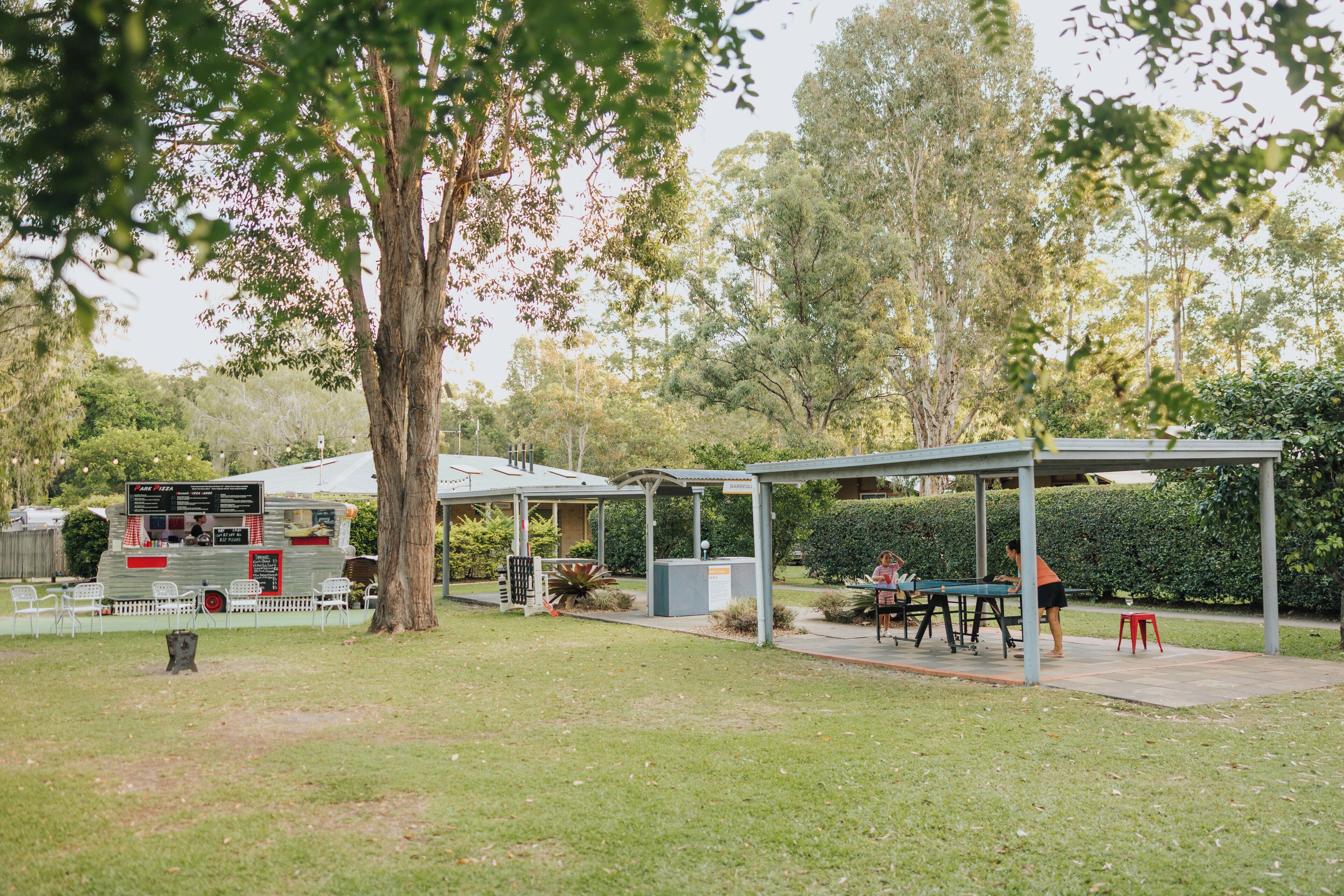 Un espace extérieur aménagé avec des tables et des chaises, un pavillon couvert et un camion-restaurant.