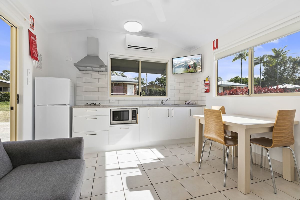 A compact kitchen with white cabinets, a built-in microwave, and a window overlooking a scenic view.