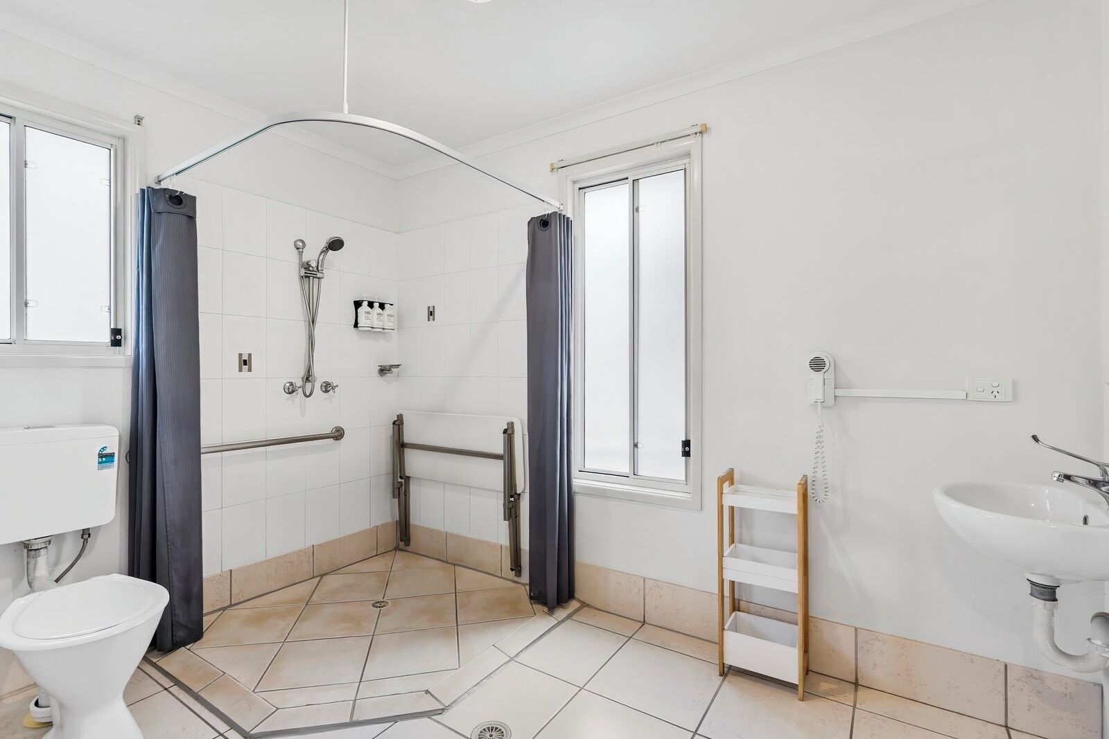 A bathroom with a shower, toilet, sink, and a window.