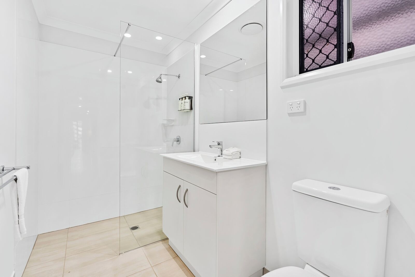 A modern bathroom with a glass-enclosed shower, a white sink, and a toilet.