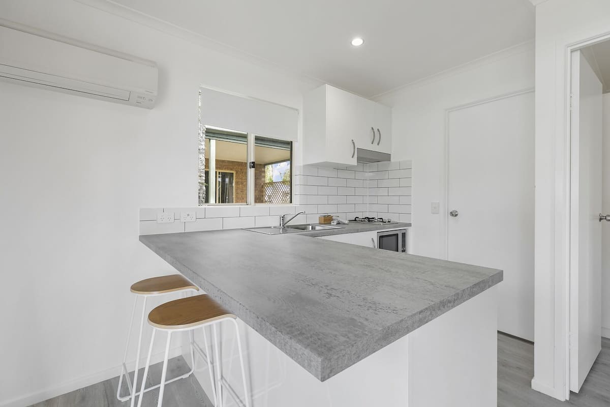 A modern kitchen with a large island, white cabinetry, and a view of the outdoors.