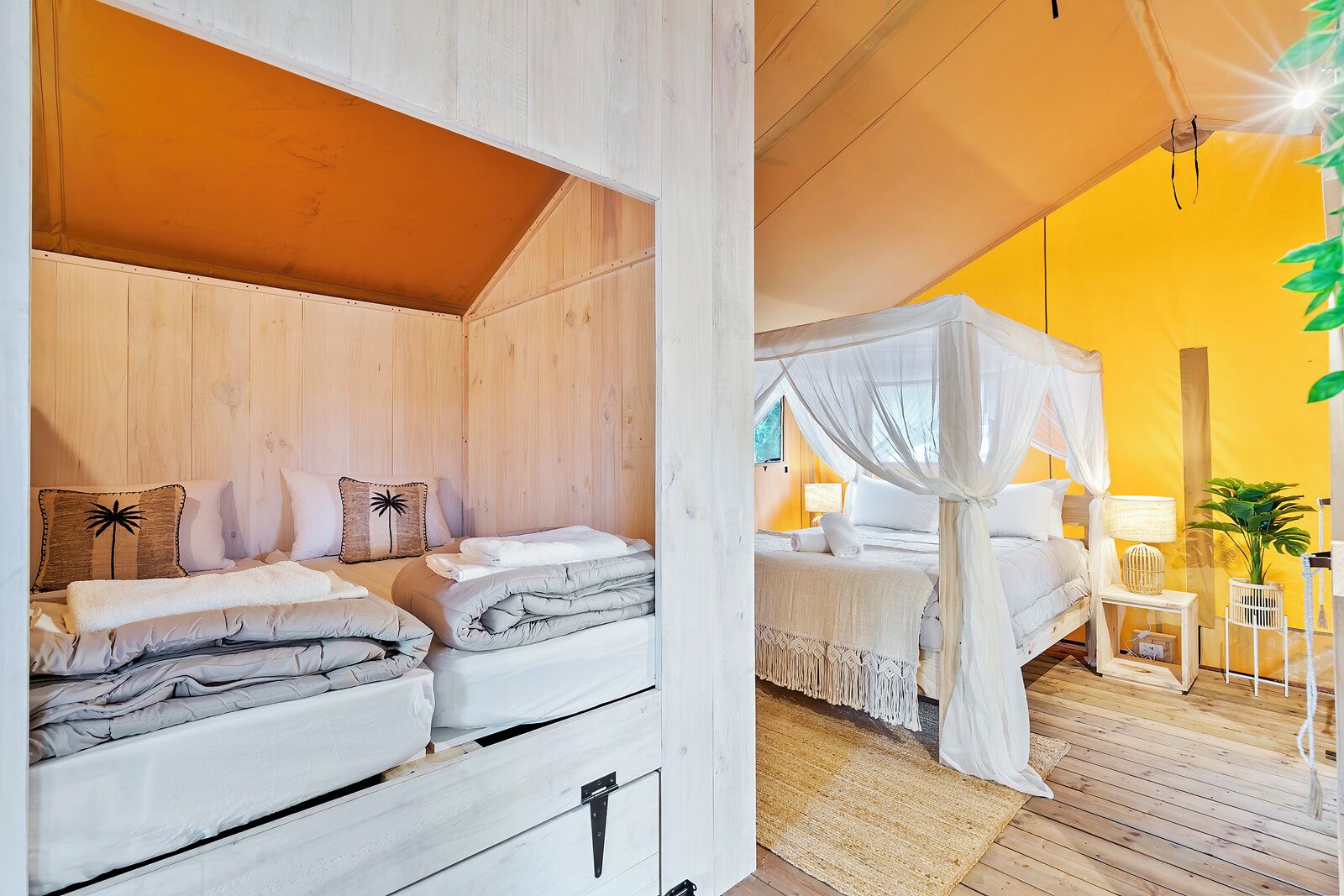 Ein Schlafzimmer mit Holzbalkendecke, einem Bett mit weißer Bettwäsche, einem Baldachinbett und einem kleinen Nachttisch mit Lampe.