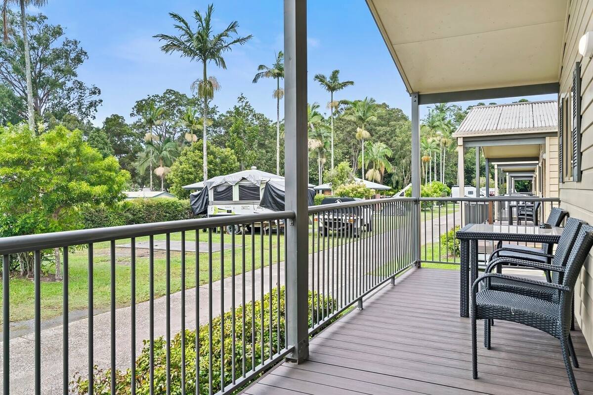 A covered outdoor area with a table and chairs, surrounded by a metal railing.
