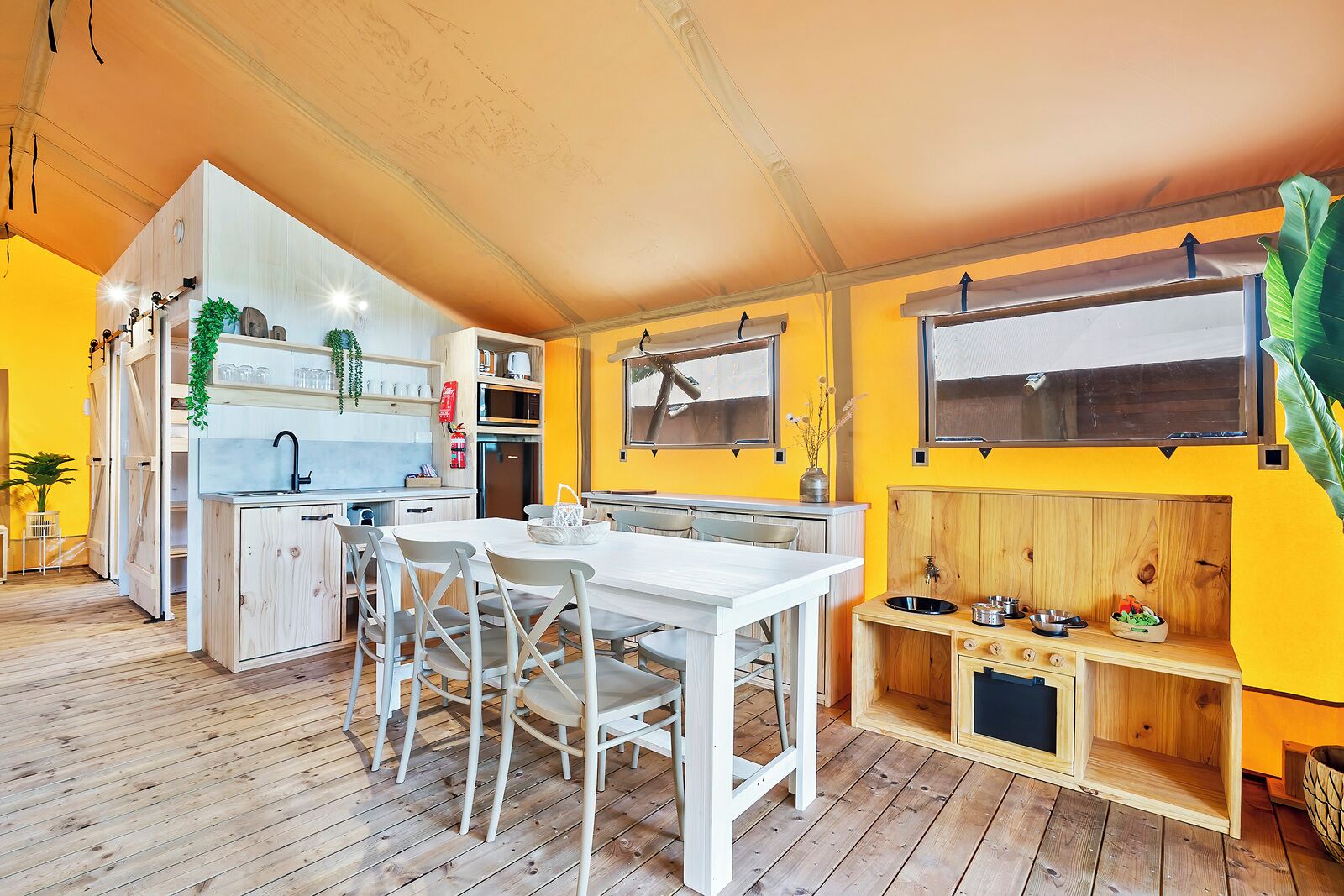 A compact kitchen with a dining area, wooden cabinets, and a window.