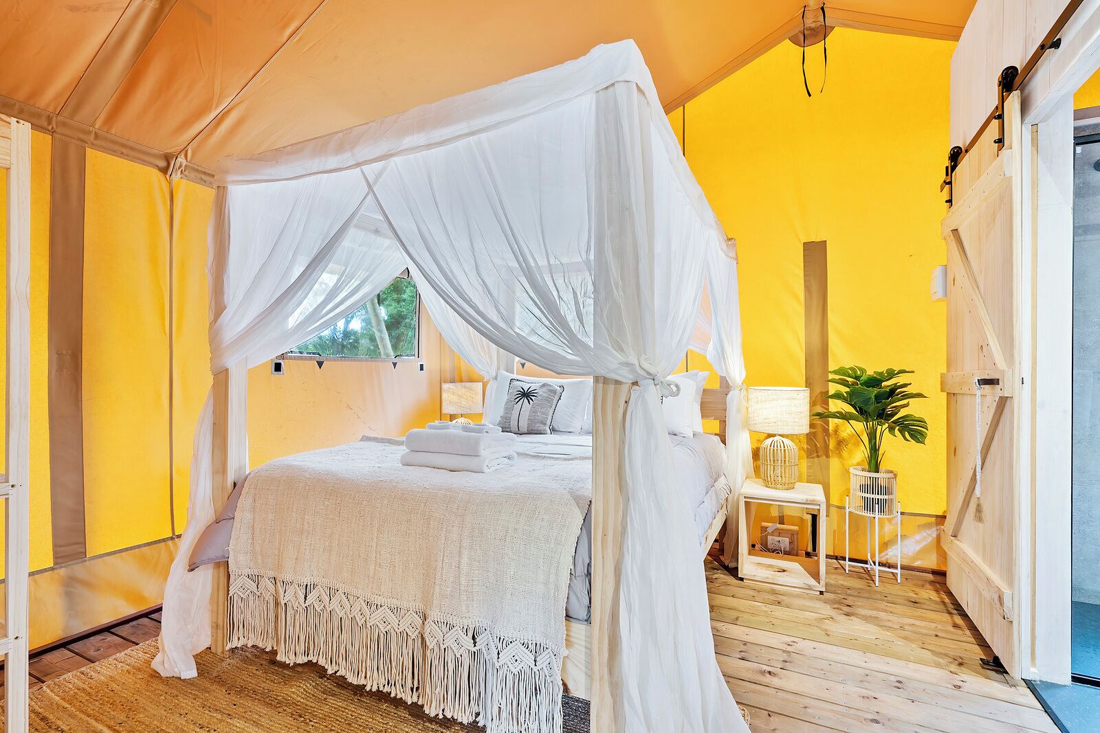 A tented room with a bed, white canopy, and a wooden floor.