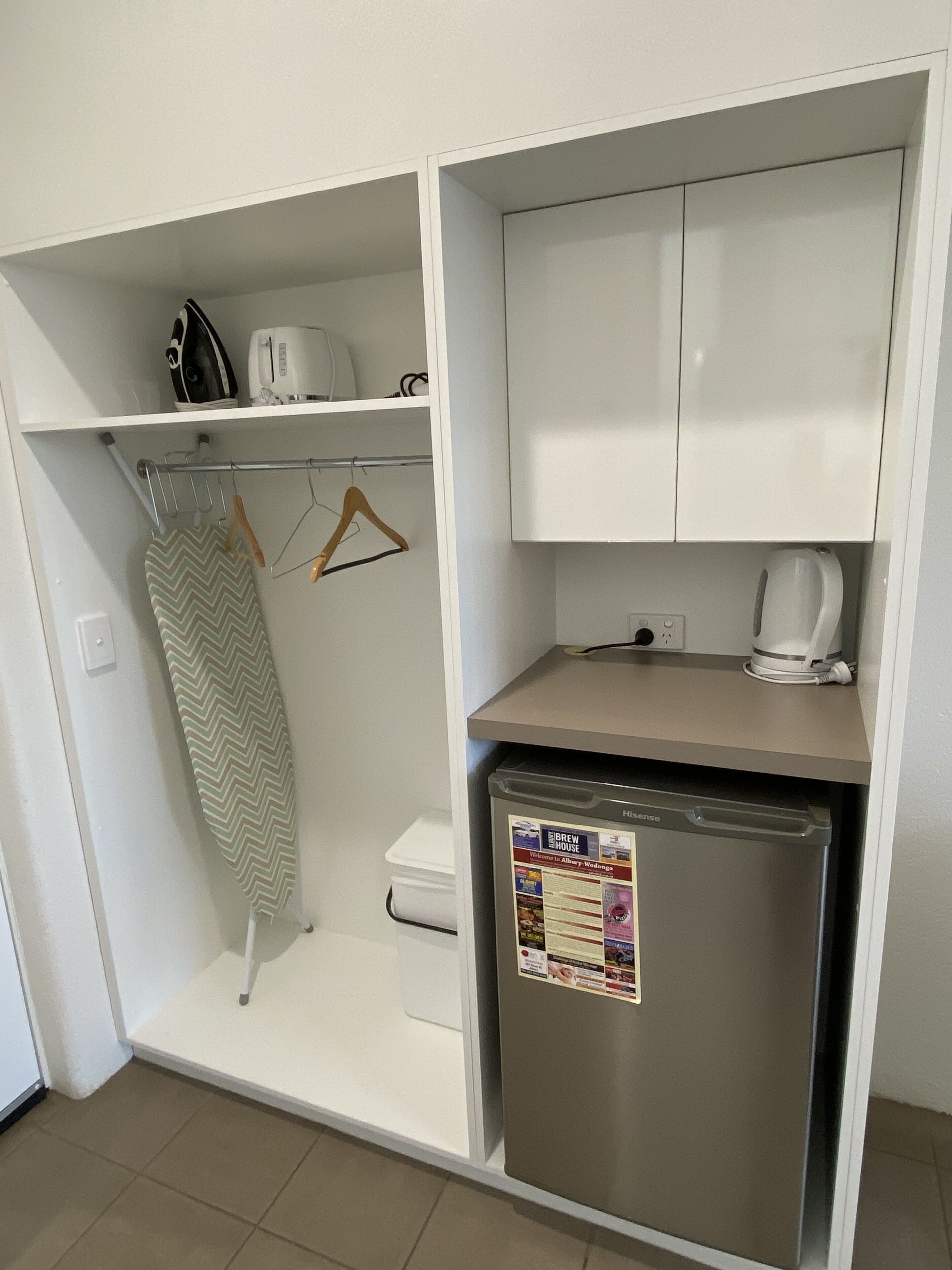 A compact kitchen with a built-in dishwasher, a kettle, and a small countertop.