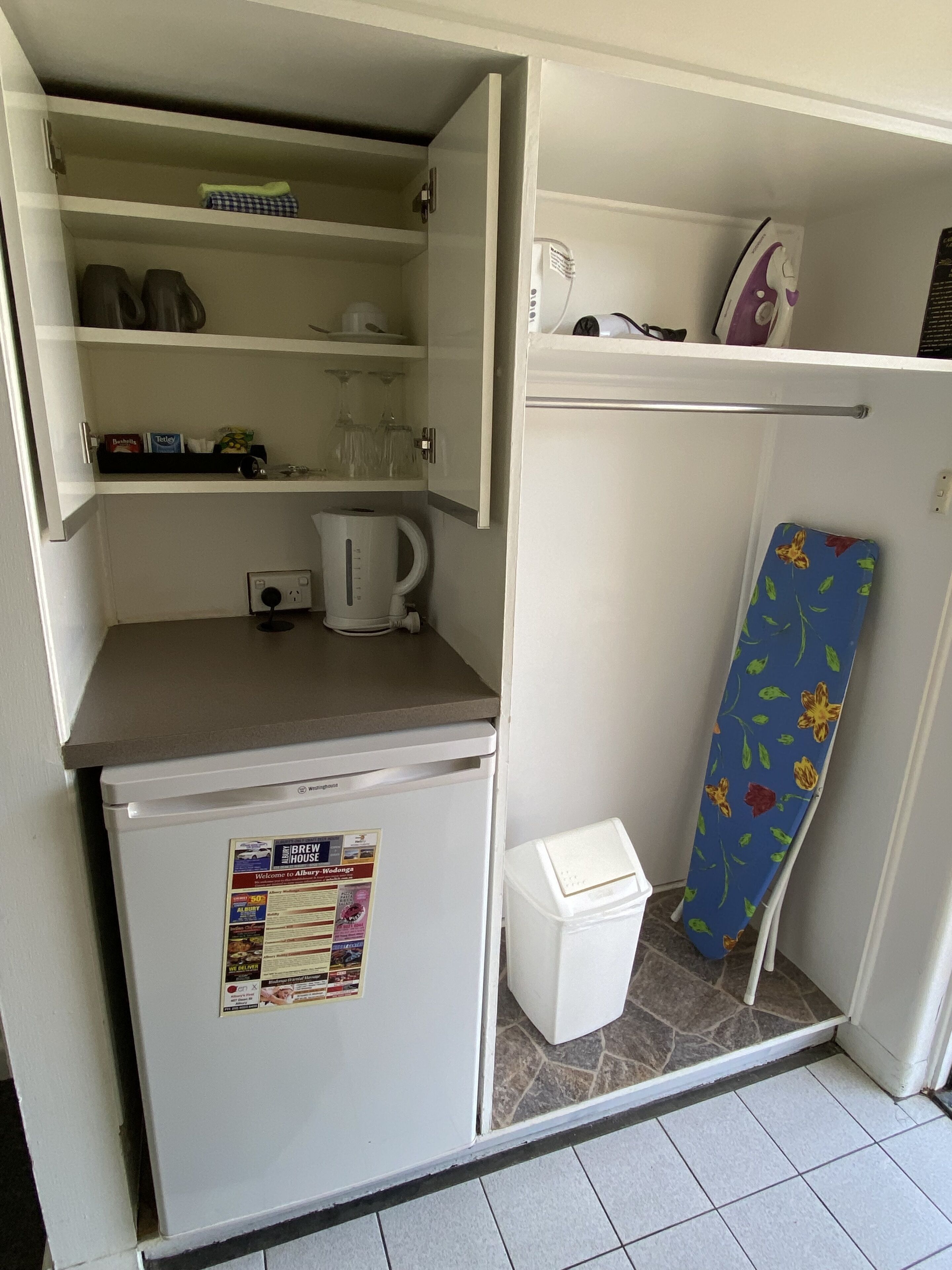 Una cocina compacta con refrigerador, hervidor y una pequeña encimera.
