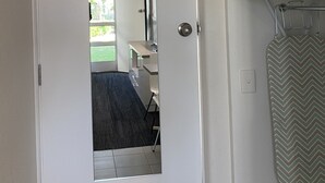 A hotel room with a white door, a mirror, a bathroom with a shower curtain, and a ceiling-mounted air conditioner. - Warrina Motor Inn Wodonga CBD (Wodonga)