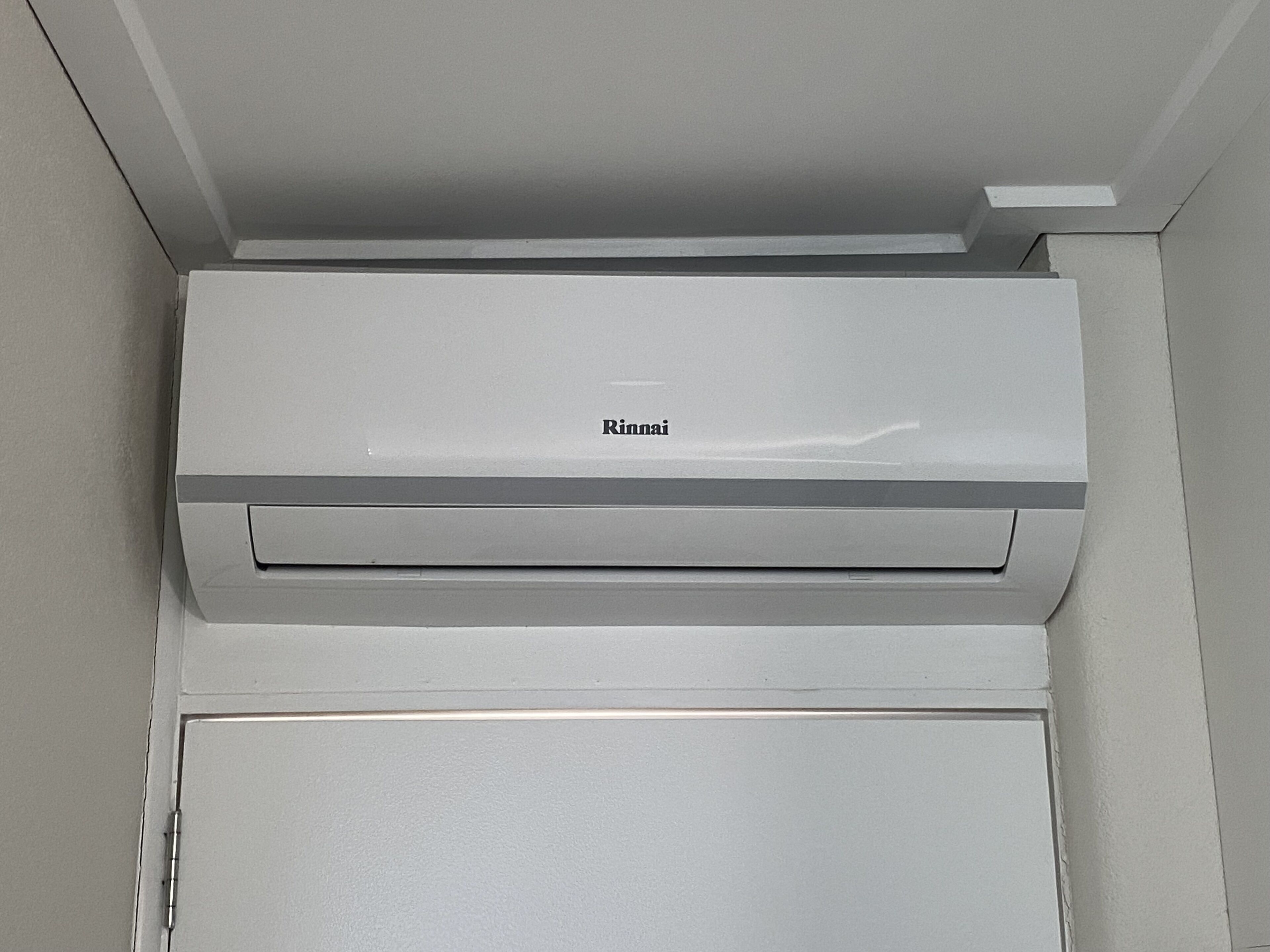 A white air conditioning unit with the brand name "Rinnai" on a wall.