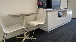 A modern hotel room with a desk, two white chairs, a flat-screen TV, a microwave, and a small cabinet. - Warrina Motor Inn Wodonga CBD (Wodonga)