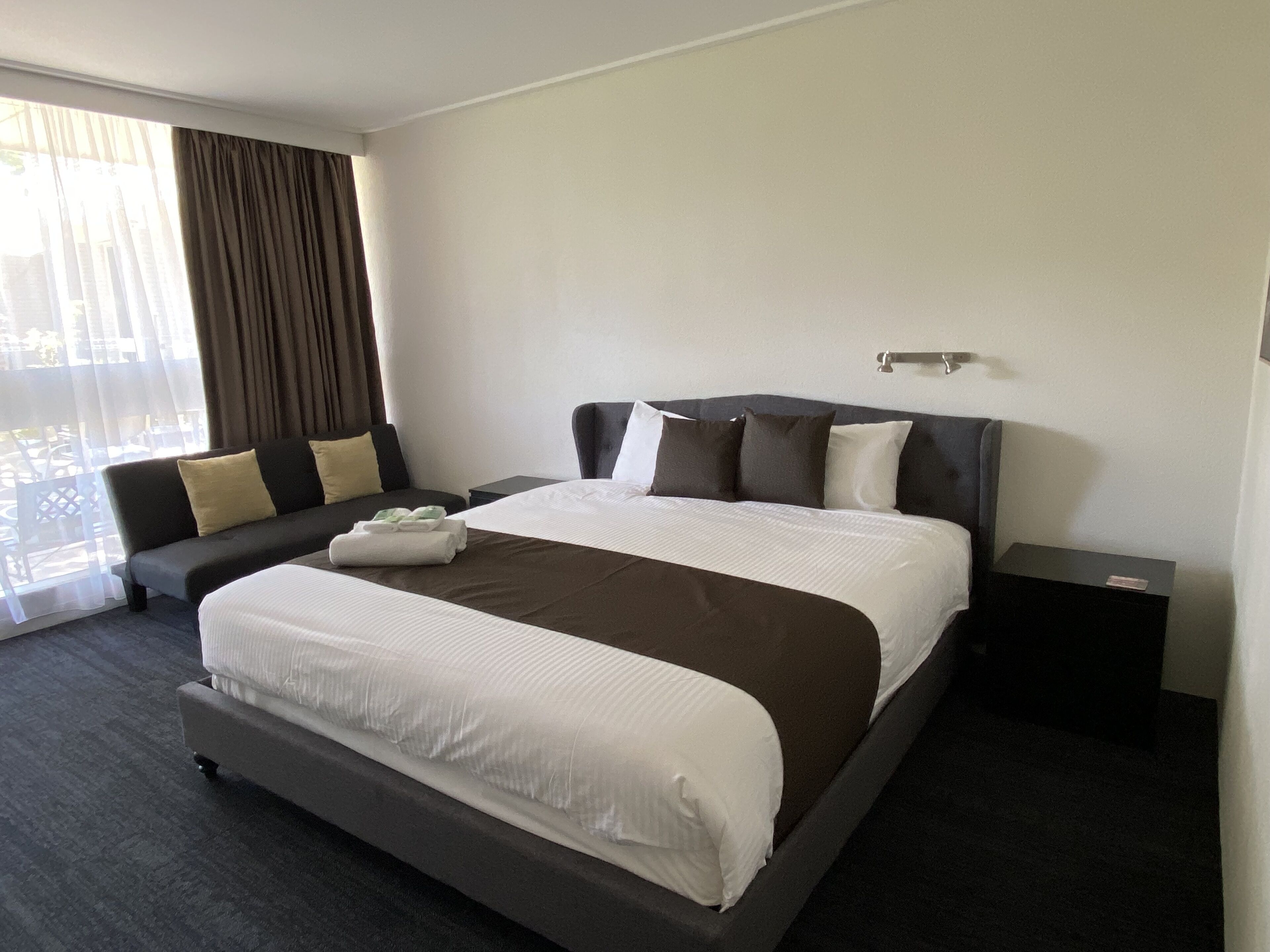 Een moderne hotelkamer met een groot bed, een bank en een kleine tafel.