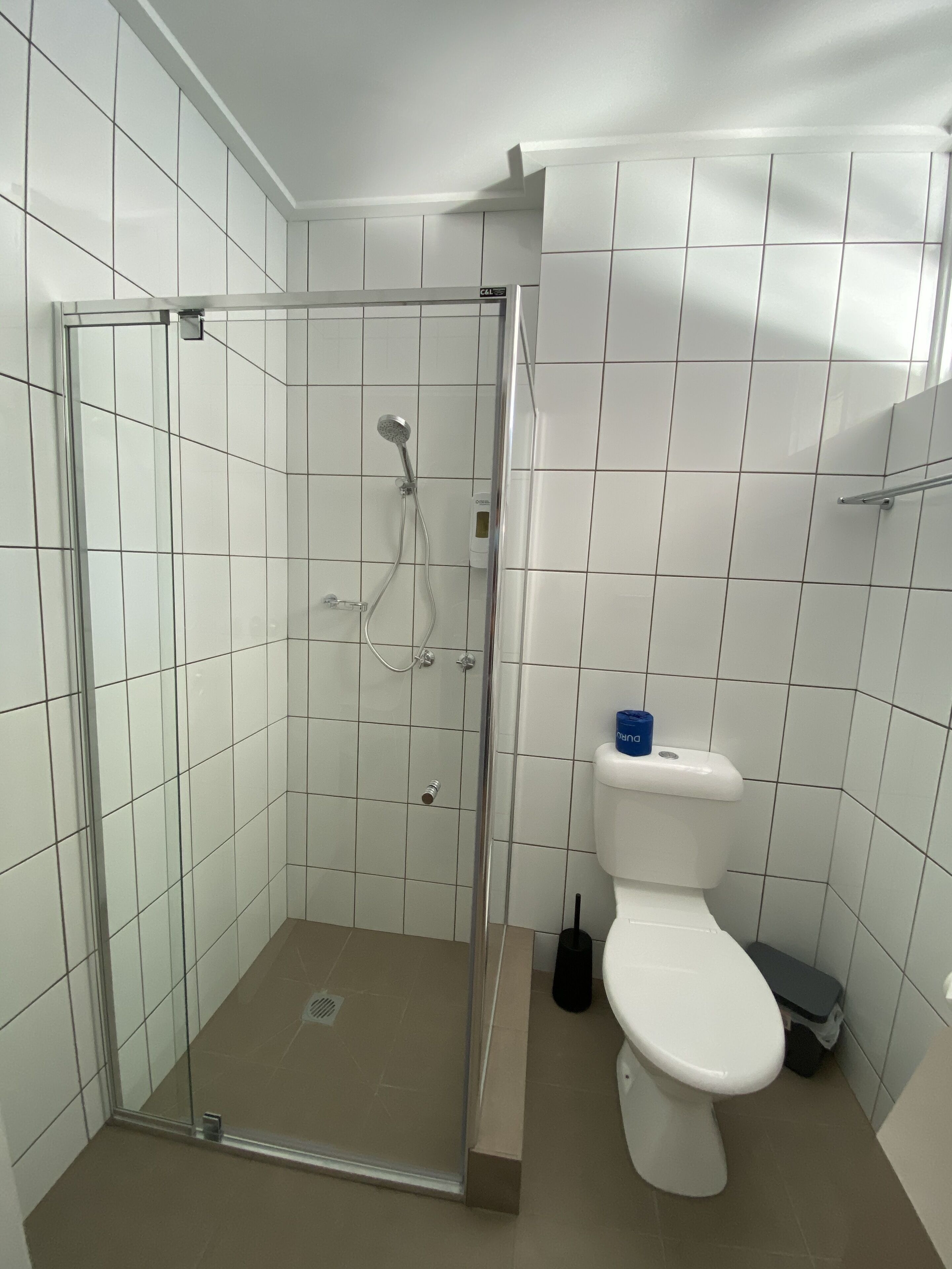 Un baño con ducha de vidrio, inodoro y lavamanos.
