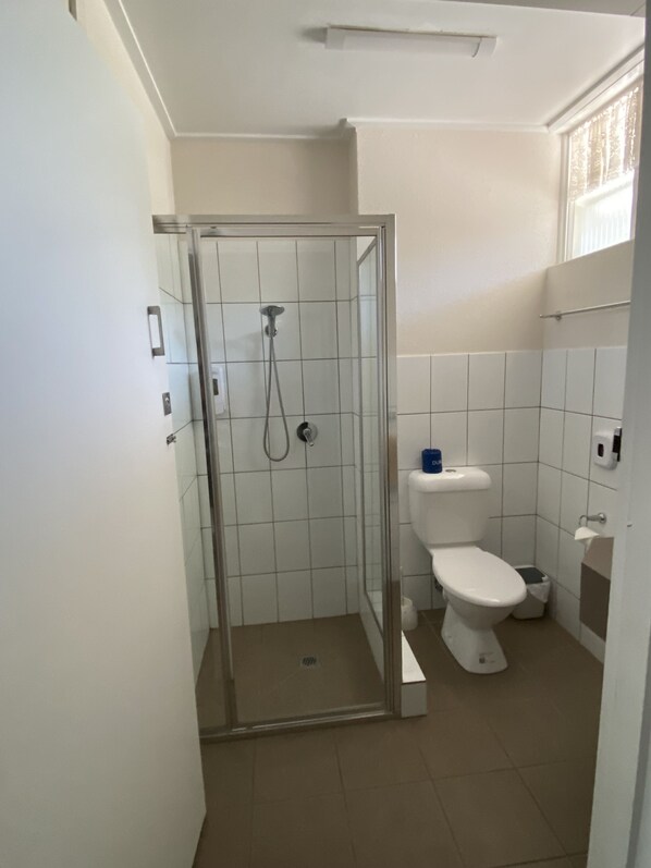 A bathroom with a glass-enclosed shower, a toilet, and a sink. - Warrina Motor Inn Wodonga CBD (Wodonga)