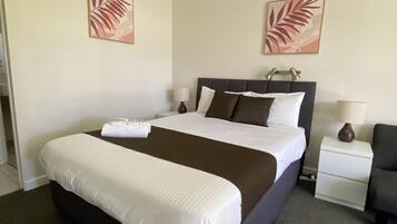 A hotel room with a large bed, two bedside tables, a chair, and two wall-mounted lamps.