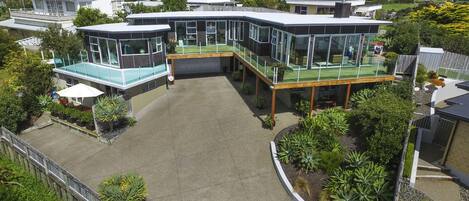 A modern house with a large patio, glass-enclosed rooms, and a view of the surrounding landscape.