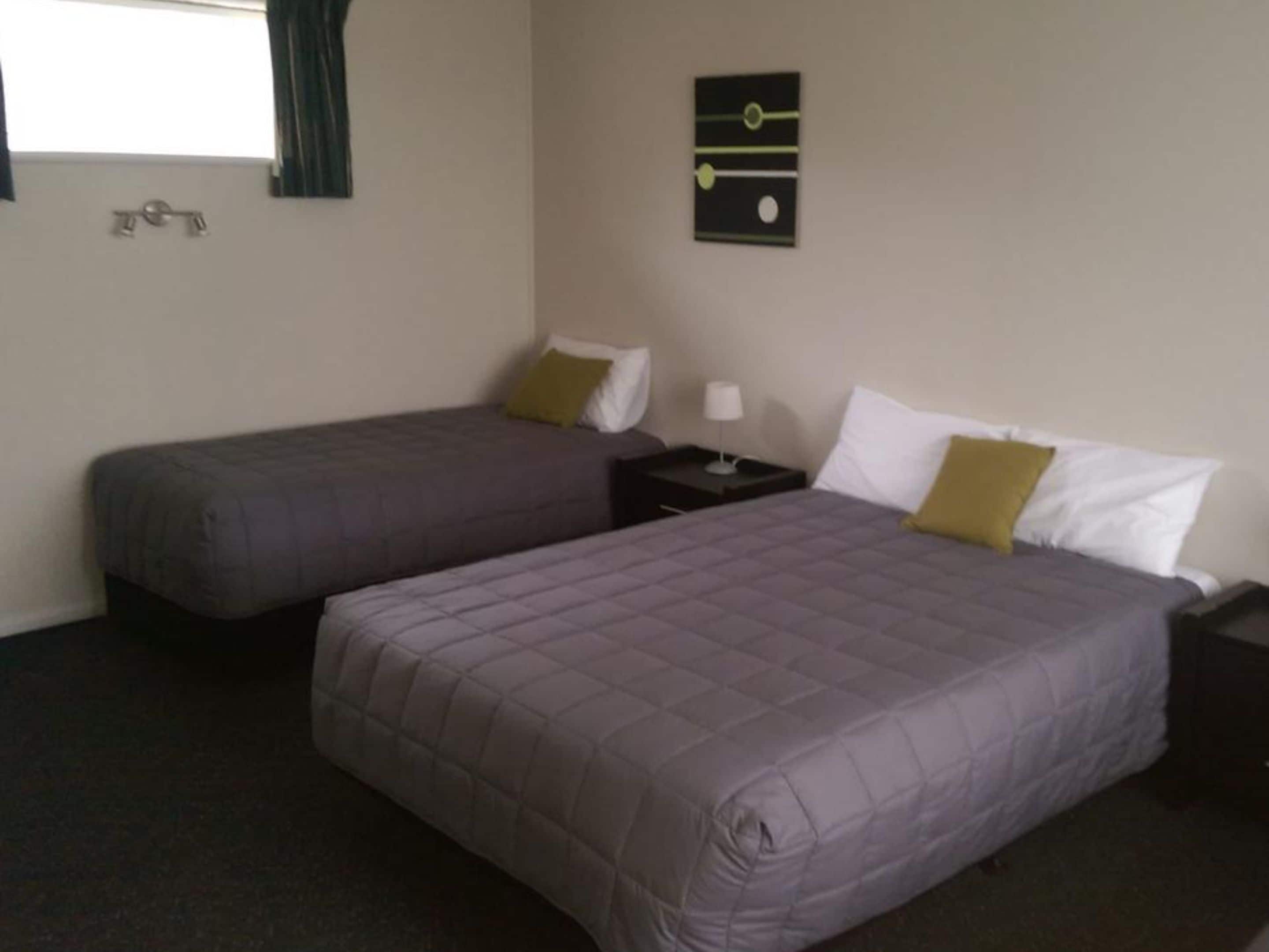 A hotel room with two beds, each with a pillow and a nightstand.
