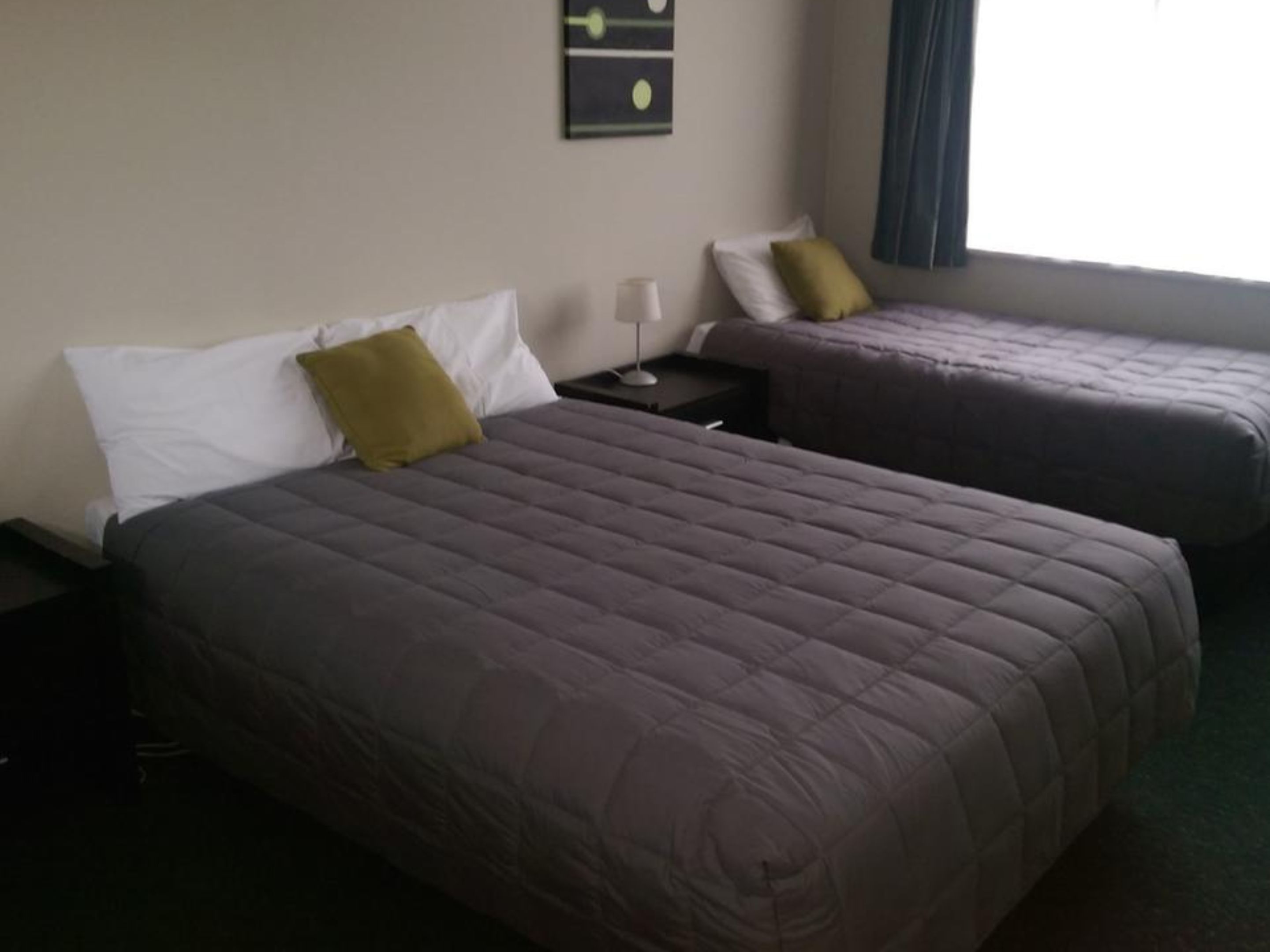 Habitació d'hotel amb dos llits, cada un amb un coixí i una tauleta de nit.