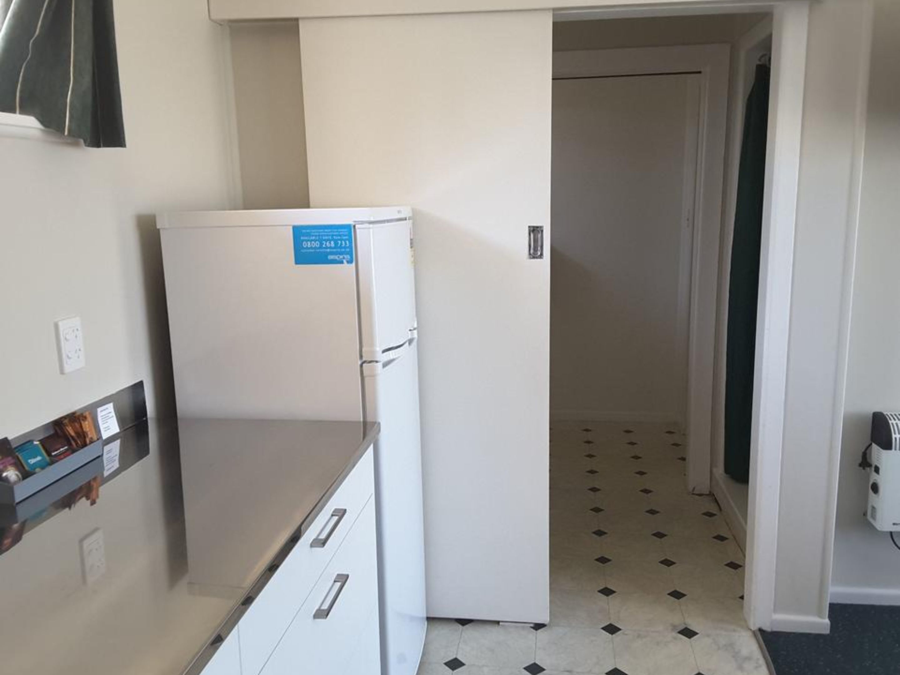 Una cocina compacta con un refrigerador blanco, una pequeña encimera y piso de baldosas.