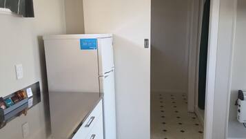Una cocina compacta con un refrigerador blanco, una pequeña encimera y piso de baldosas.