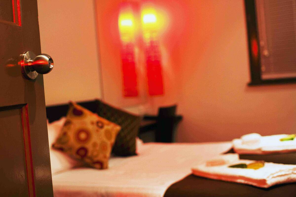 A hotel room with a bed, pillows, and a nightstand.