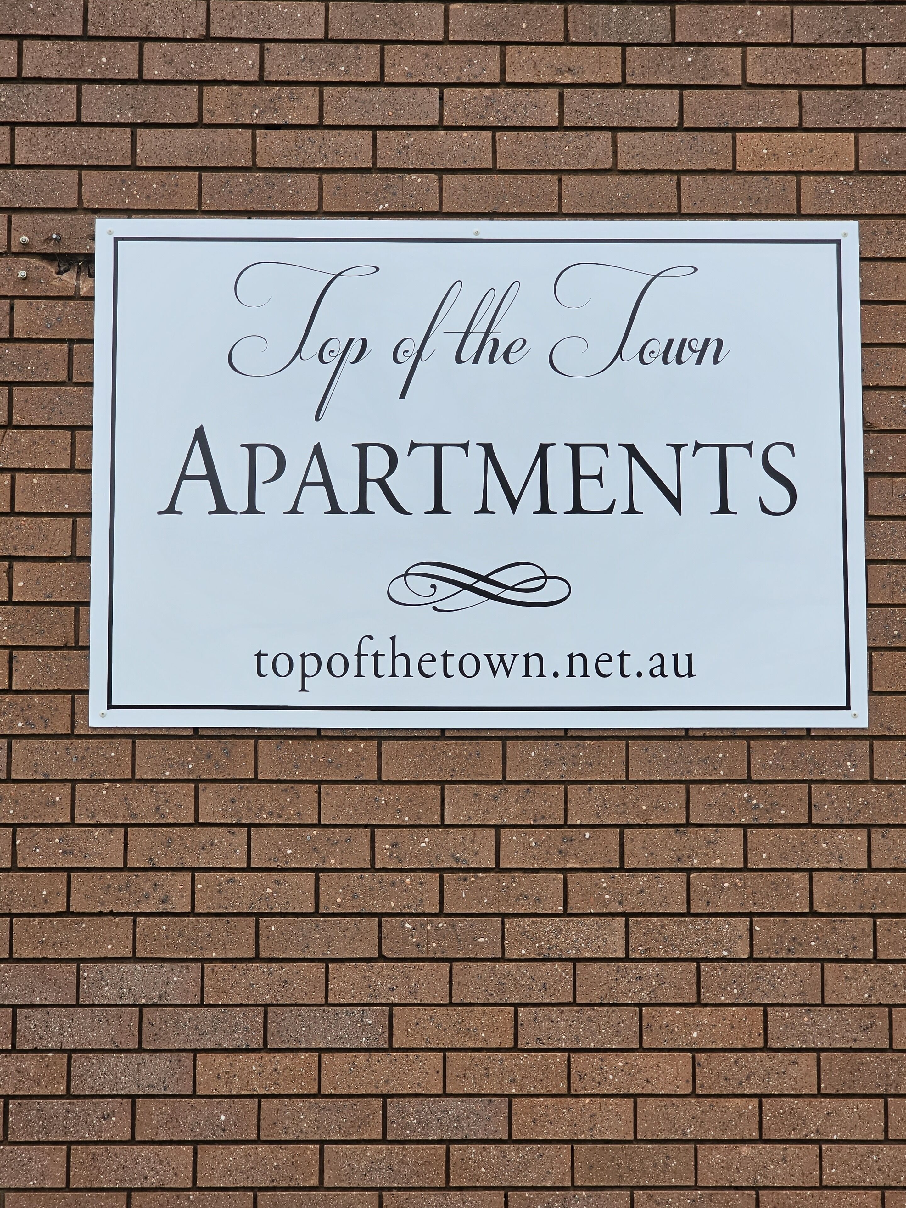 Un letrero que anuncia Apartamentos Top of the Town, con una dirección web.