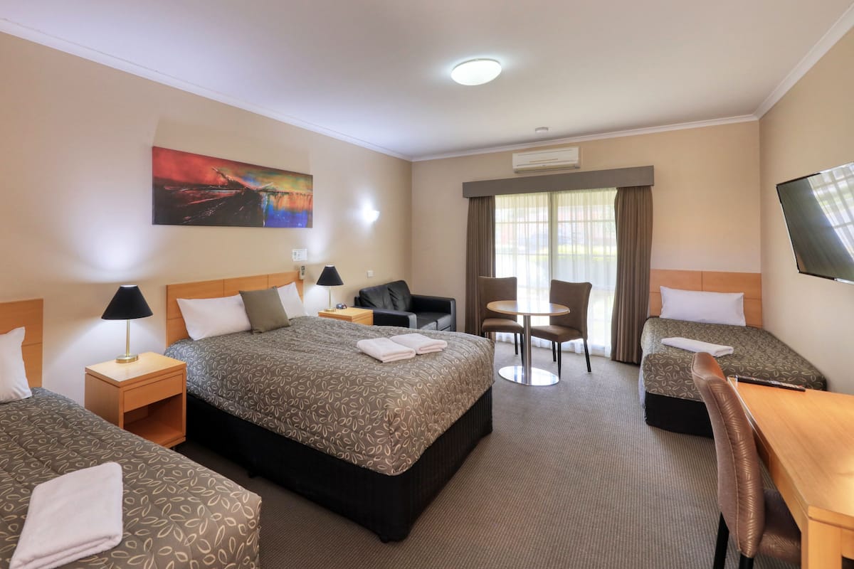 Une chambre d’hôtel avec deux lits, un bureau, une chaise et un téléviseur.