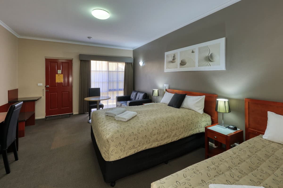 Une chambre d’hôtel avec un grand lit, un bureau, une chaise, une petite table et un téléviseur.