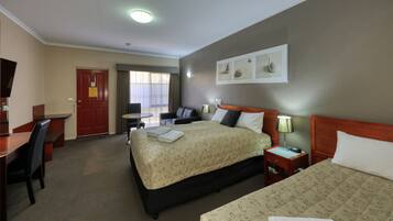 A hotel room with a large bed, a desk, a chair, a small table, and a TV.