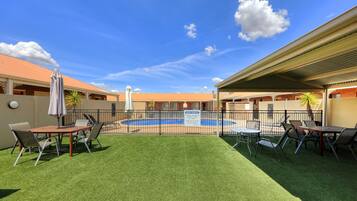 A fenced outdoor area with a pool, tables, and chairs, and a sign requesting guests to vacate by 10pm.