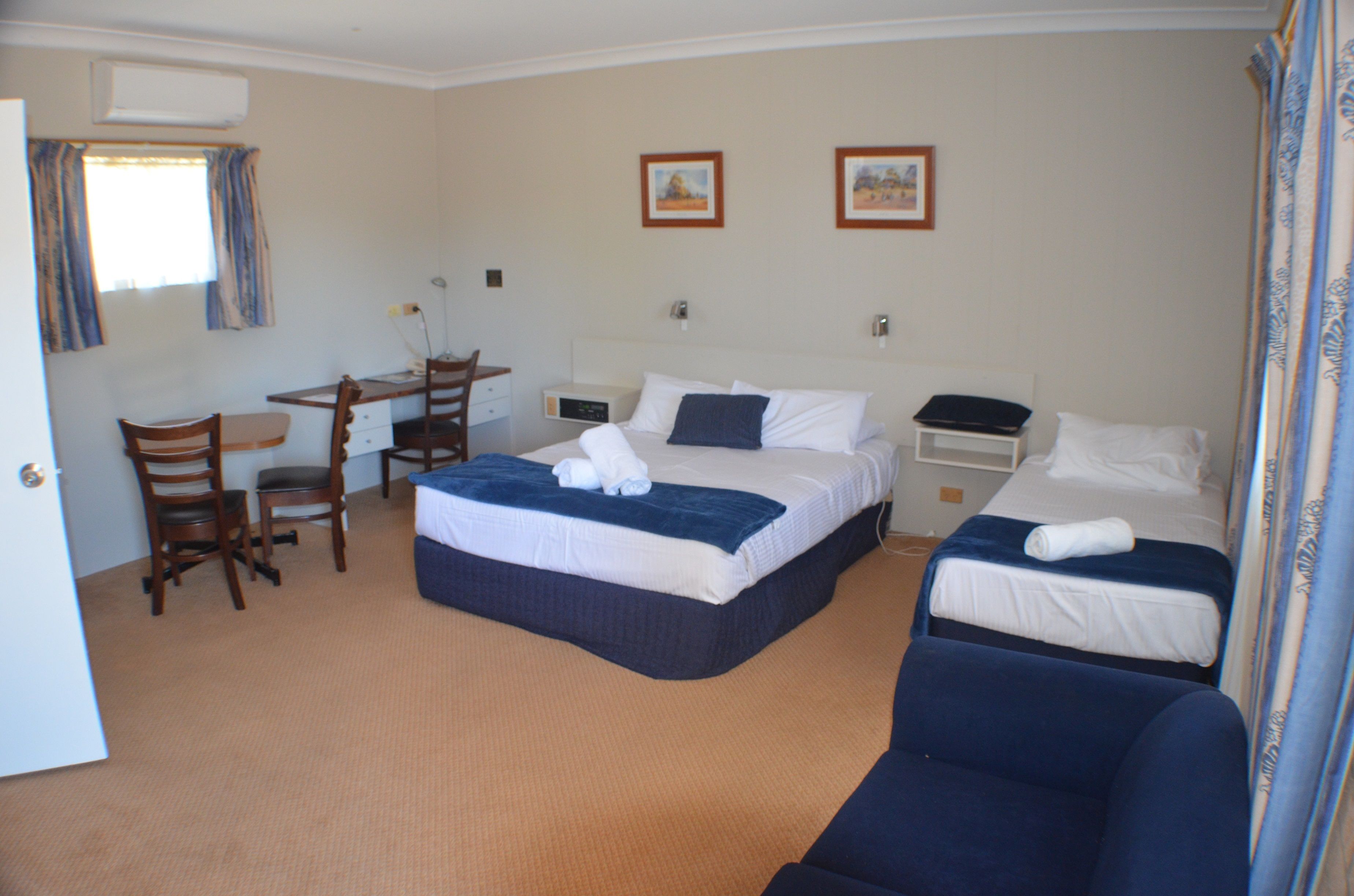 A hotel room with two beds, a desk, and a chair.