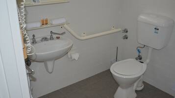 A small, clean bathroom with a sink, toilet, and a grab bar.