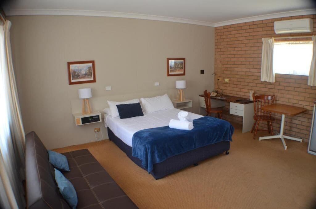 Una habitación de hotel con cama, escritorio, silla y una mesita.