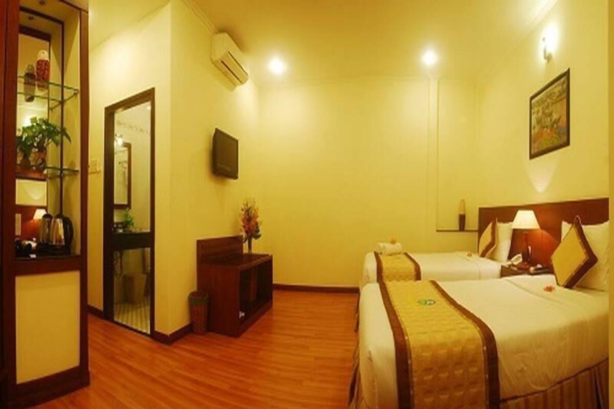 A hotel room with two beds, a small desk, a mirror, and a television.