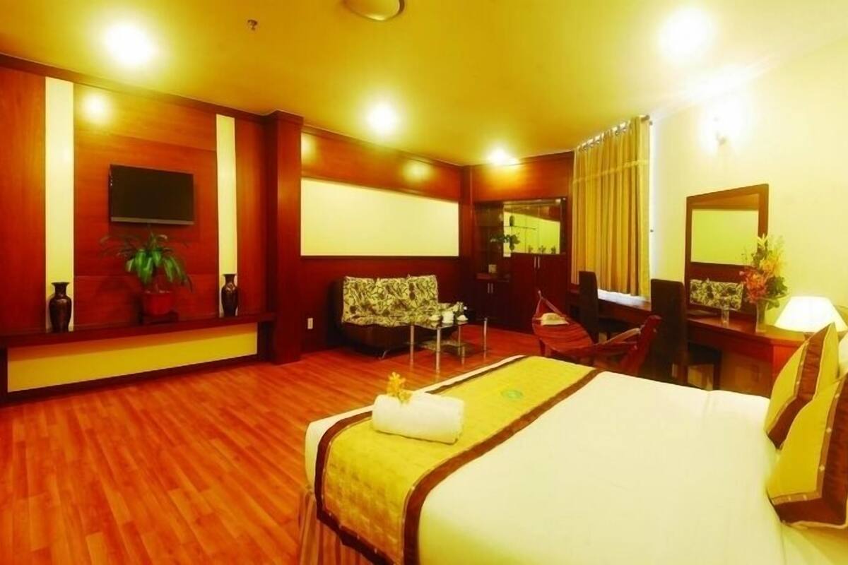 A hotel room with a bed, a desk, a chair, a television, and a mirror.