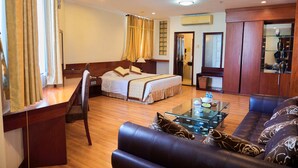 Habitación de hotel con una cama, un sofá, una mesa de centro de vidrio y un escritorio.
