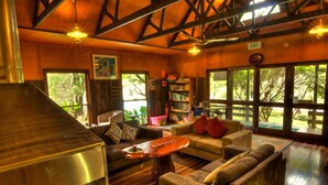 A cozy living room with a fireplace, comfortable seating, and large windows offering a view of the outdoors. - Broken River Mountain Resort (Broken River)
