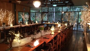A restaurant with long wooden tables set for dining, large windows, and decorative lighting. - Broken River Mountain Resort (Broken River)