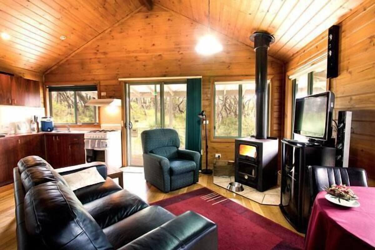 A cozy cabin interior with a fireplace, leather sofa, and a dining area.