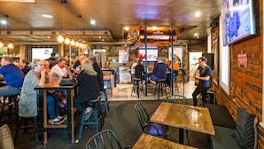 A restaurant with wooden tables and chairs, a stage for live music, and a TV screen on the wall. - National Hotel Complex and Bendigo Central Apartments (Bendigo)