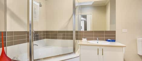 A modern bathroom with a glass-enclosed bathtub, a white sink, and a mirror above the sink.