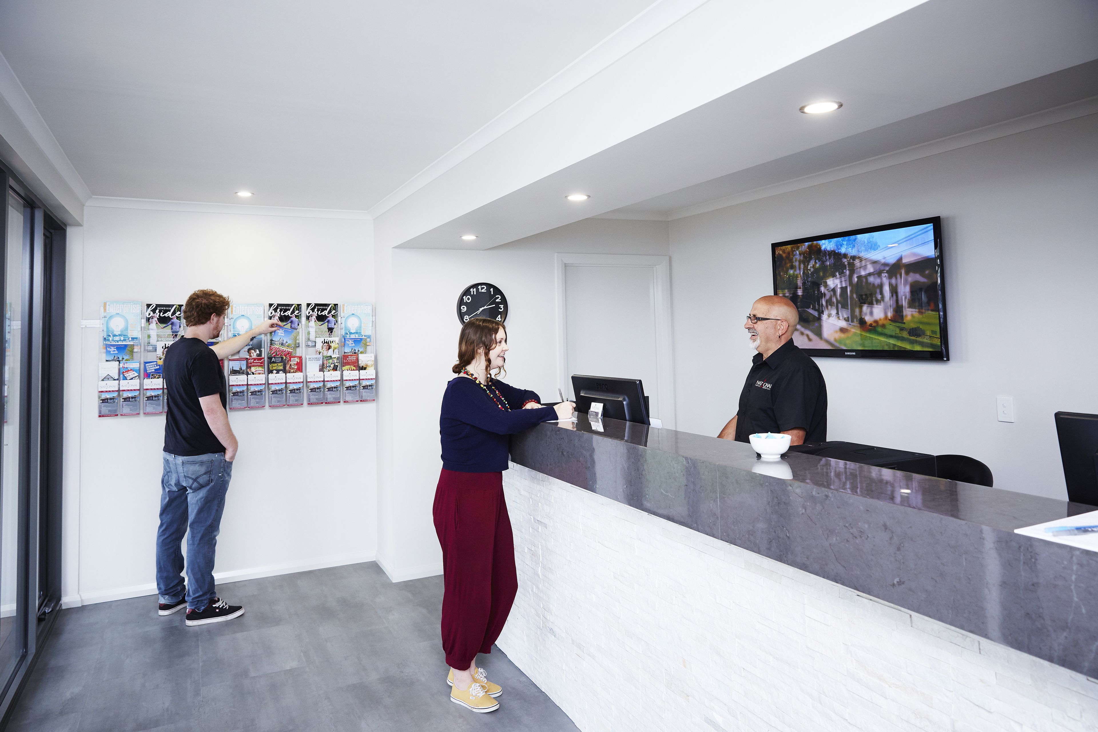 Un espace d’accueil avec un comptoir en marbre, une horloge et un tableau encadré au mur.