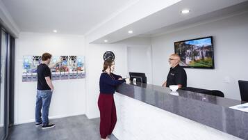 Un espace d’accueil avec un comptoir en marbre, une horloge et un tableau encadré au mur.