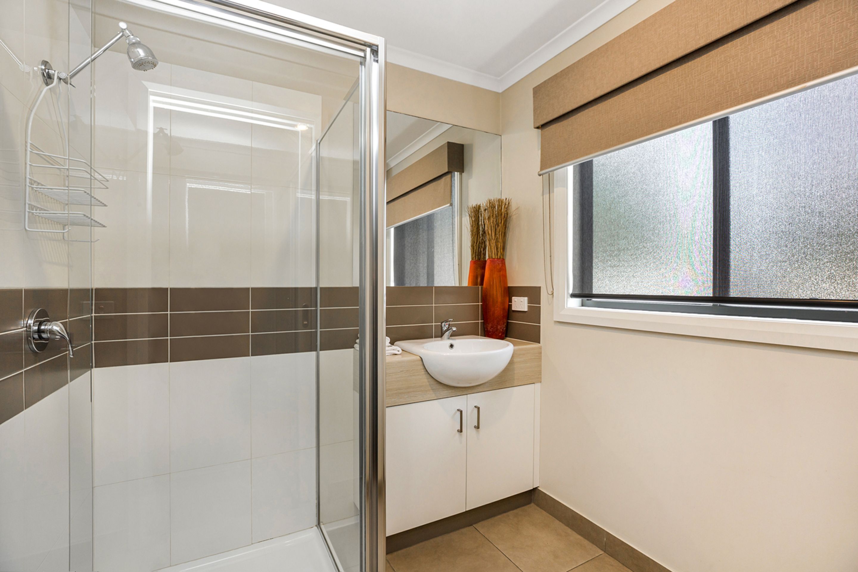 Ein modernes Badezimmer mit Duschkabine aus Glas, einem weißen Waschbecken und einem Fenster mit Blick.