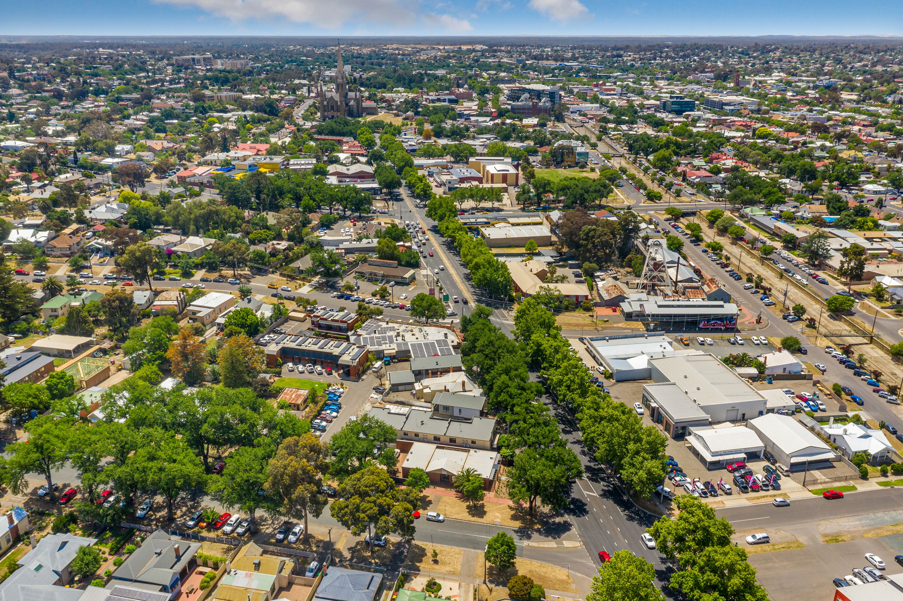 Vista aérea de un paisaje urbano con edificios residenciales y comerciales, calles y áreas verdes.