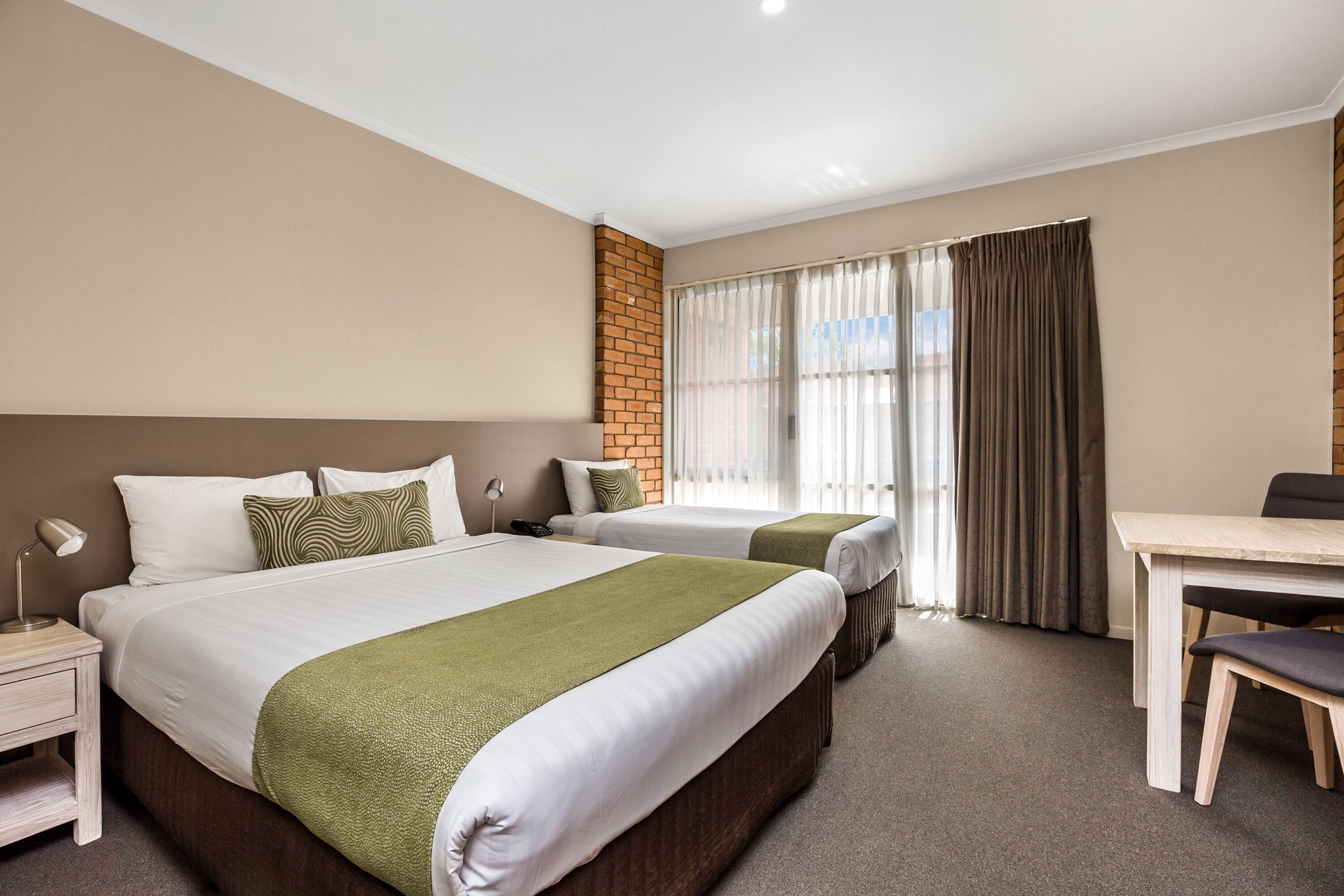 Een hotelkamer met twee bedden, een bureau en een stoel.