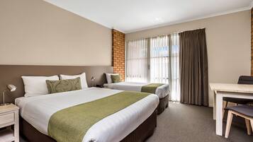 A hotel room with two beds, a desk, and a chair.