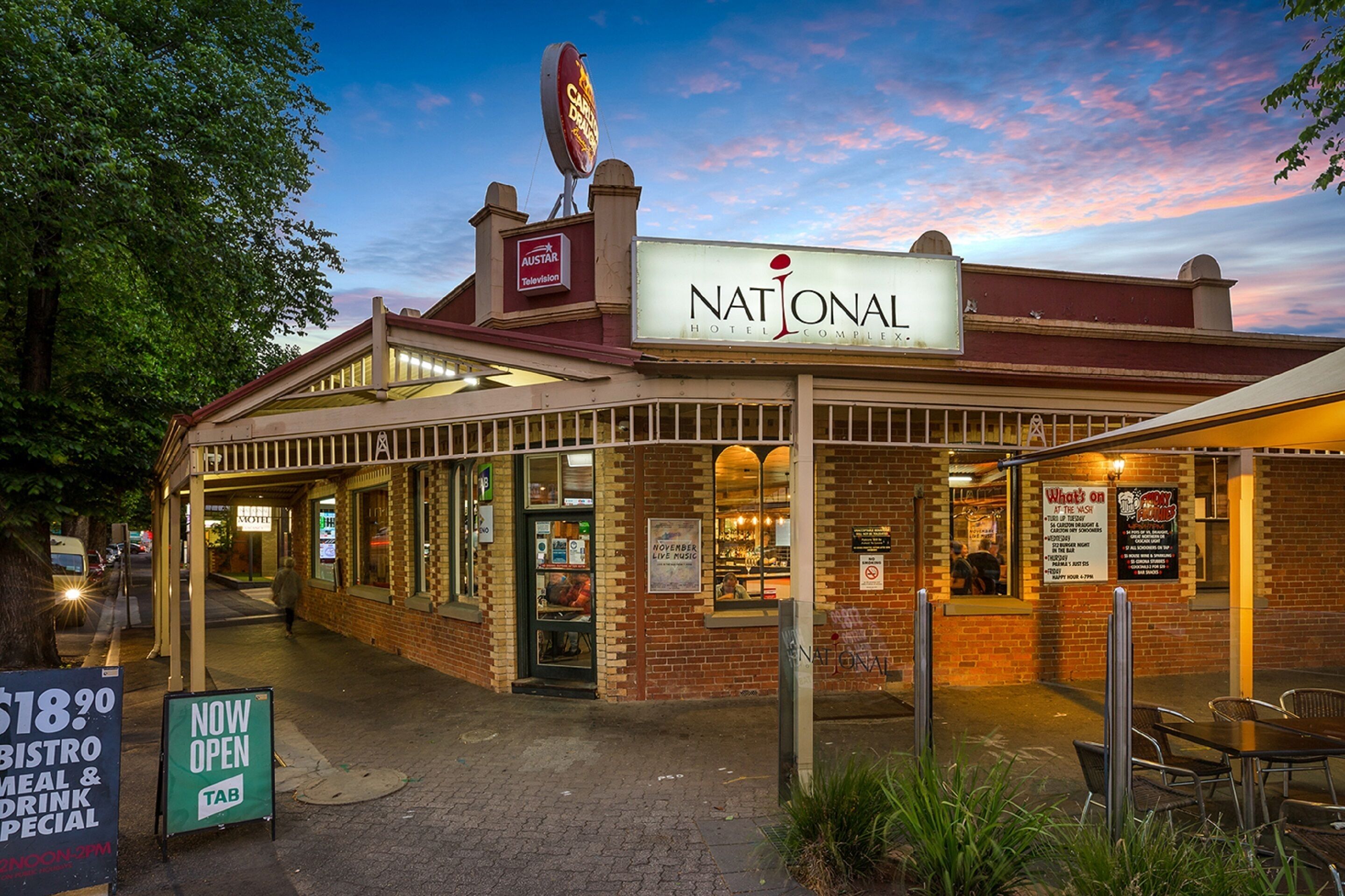 A National Hotel with a brick facade, outdoor seating, and a sign indicating a new open bistro.